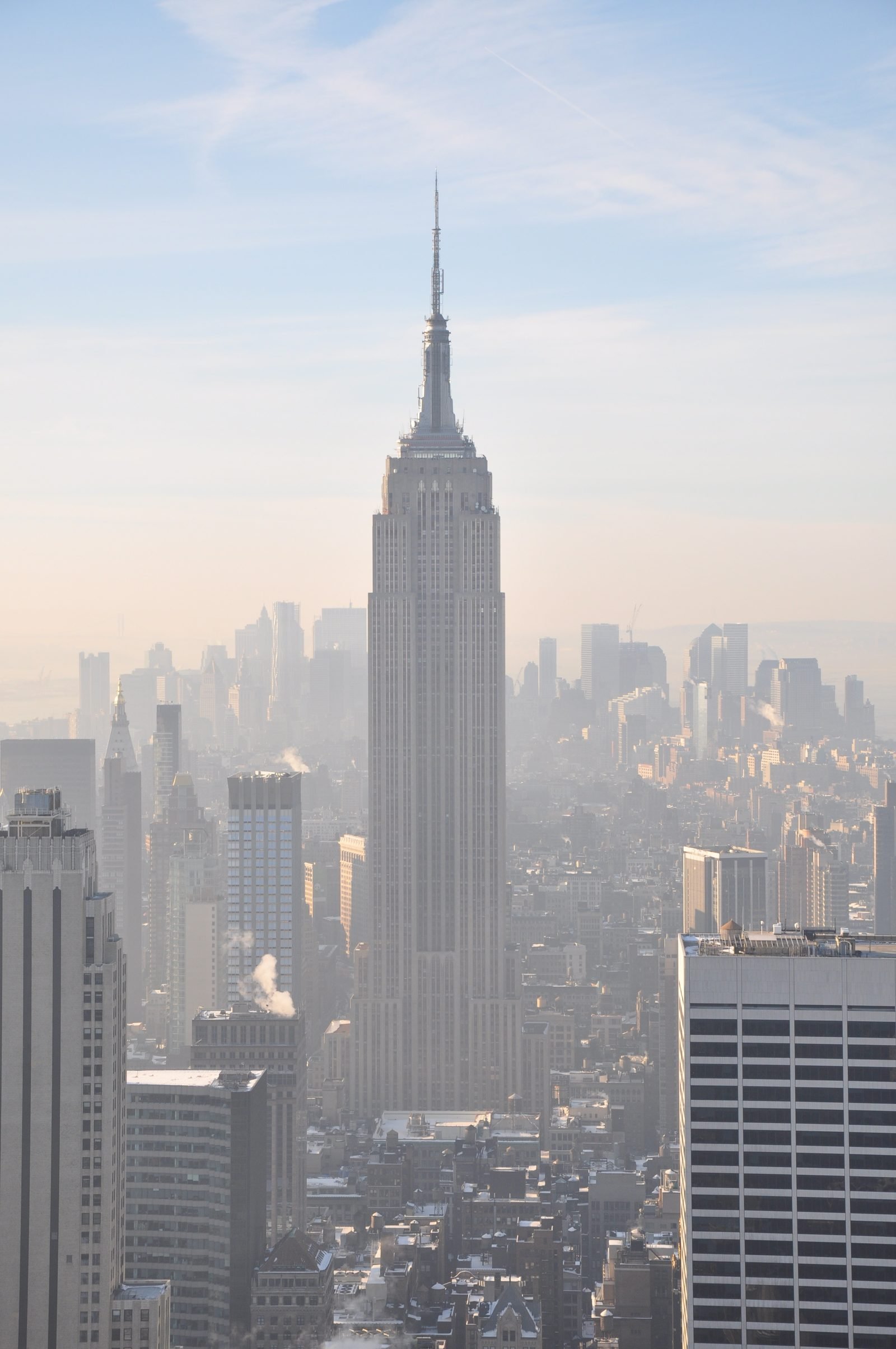 The Empire State Building seen from above, with the antenna on top, among the buildings of Manhattan on a hazy morning