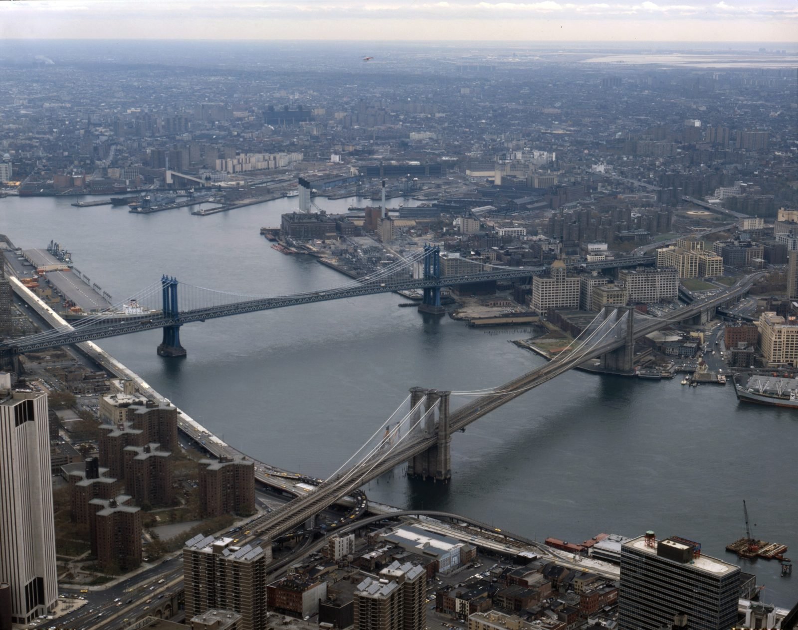 Aerial view of the East River with the Brooklyn Bridge running diagonally in the foreground and the Manhattan Bridge just behind it