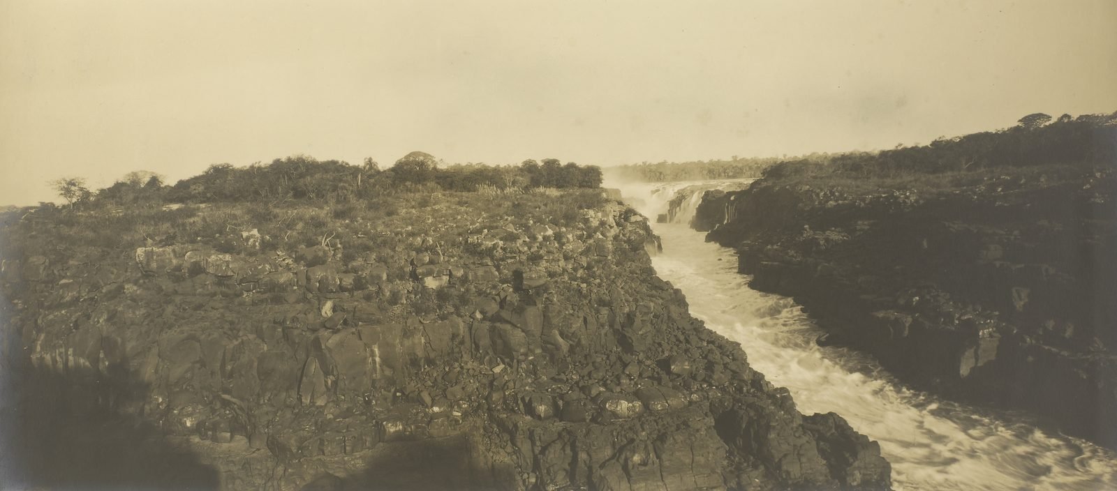Old sepia photograph of the Paraná River squeezed between rock walls at the Sete Quedas falls, with waterfalls in the background