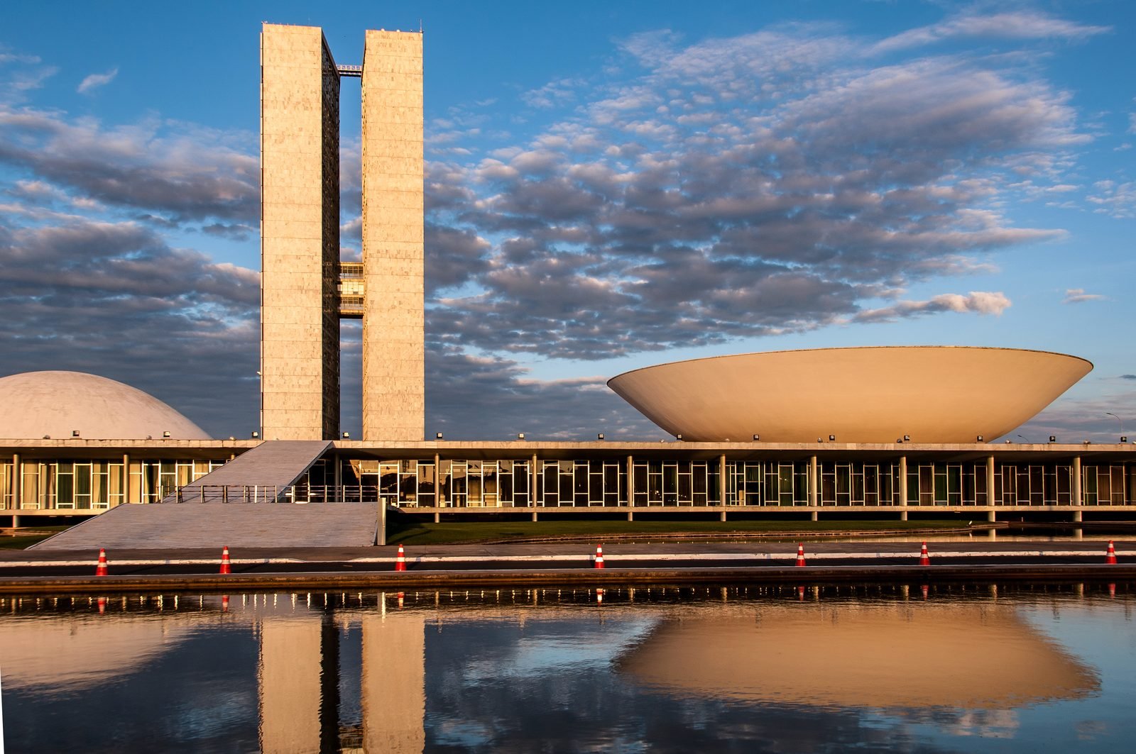 The National Congress at dusk, with the two tall towers on the left, the convex Senate dome at the edge, the large concave Chamber dome on the right and the whole complex reflected in the reflecting pool